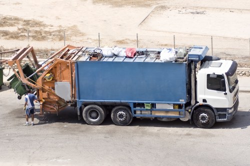 Staff loading waste into a skip while wearing hi-vis gear